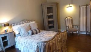 a bedroom with a large bed and a chair at Le Logis BnB in La Trimouille