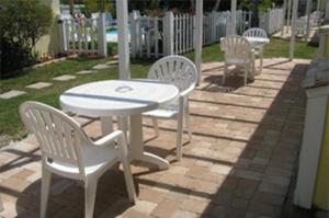 a group of white chairs and a table and chairs at Queens Gate Resort in Bradenton Beach