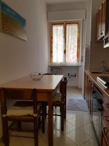 uma cozinha com uma mesa e cadeiras de madeira e uma janela em Appartamento Soleluna em Parma