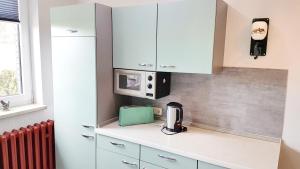 a kitchen with white cabinets and a microwave at Monis gemütliche Ferienwohnungen in Suhl