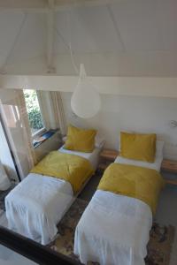 een kamer met 2 bedden en gele kussens bij B&B Achterom in Loon op Zand