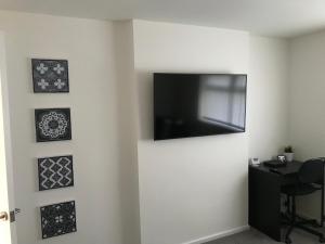TV de pantalla plana en una pared blanca con cuadros en Property Hunter 25 en Darlington