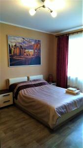 Comfort Apartments في فيليكي نوفغورود: غرفة نوم بسرير كبير عليها لوحة على الحائط