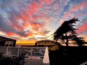 einen Sonnenuntergang auf dem Balkon eines Hauses mit einem Baum in der Unterkunft Captain's Inn at Moss Landing in Moss Landing