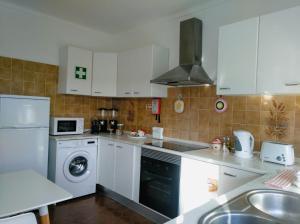 a kitchen with white cabinets and a washer and dryer at Casa Vaz in Grândola