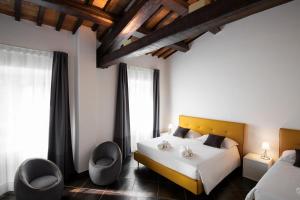 ComunanzaにあるInteramnia Boutique Hotelのベッド1台と椅子2脚が備わるホテルルームです。