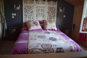 a bedroom with a bed with a purple and white blanket at La mare aux Canards, 8mn du Zoo de Beauval in Châteauvieux
