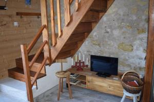 a living room with a tv and a wooden staircase at La mare aux Canards, 8mn du Zoo de Beauval in Châteauvieux