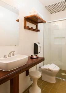 a bathroom with a sink and a toilet and a mirror at Hotel Porto Di Mare in Ubatuba