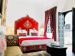 um quarto vermelho e branco com uma cama e uma cadeira em Maison Chafia Boutique Hôtel & Spa em Marraquexe