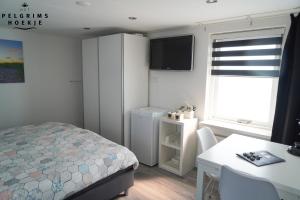 a bedroom with a bed and a table and a window at Het Pelgrimshoekje in Vrouwenpolder