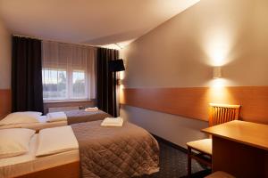 キェルツェにあるHotel Wenaのベッド2台とデスクが備わるホテルルームです。