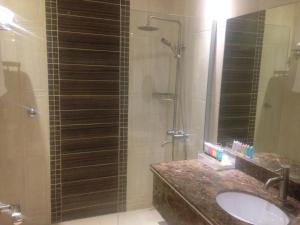 a bathroom with a sink and a shower with a mirror at Arjaan Altakhassusi Hotel Suites in Riyadh