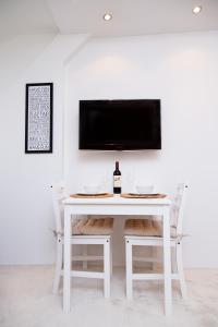 コパオニクにあるNeva Apartment Angella Konaciの白いテーブル(椅子付)、壁掛けテレビ