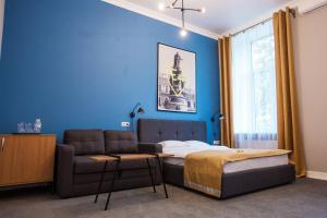 1 dormitorio con cama, sofá y pared azul en E4 Hotel, en Odessa