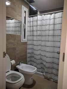 y baño con aseo y cortina de ducha. en DEPARTAMENTO Edificio LEONARDO en Villa Carlos Paz
