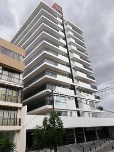 un edificio blanco alto con un letrero. en DEPARTAMENTO Edificio LEONARDO en Villa Carlos Paz