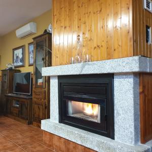 a stone fireplace in a living room with a tv at El Jardín del 22 in Trujillo