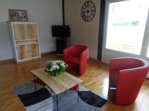 a living room with two red chairs and a table with flowers at GITE DES BOULEAUX in Maîche