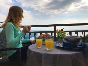 a woman sitting at a table with two glasses of orange juice at Uphill Opatija Apartment in Opatija