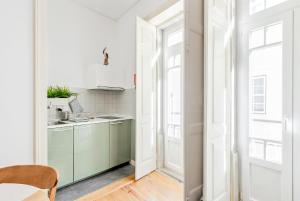 a kitchen with green cabinets and white walls and a table at Casa do Sapalinho II - Setubal Downtown in Setúbal