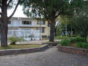 a house with a white fence and two trees at Casa Hostal Sweet Home in Bogotá