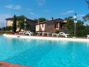 einen Pool mit Stühlen und ein Haus in der Unterkunft Borgo Il Villino in Casole dʼElsa