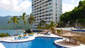 a hotel with a swimming pool and a tall building at Paraiso Azul in Acapulco