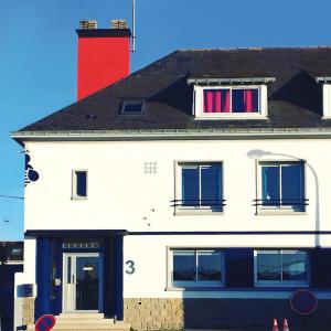 un edificio blanco con chimenea roja y 2 ventanas en Les Abeilles en Saint-Nazaire