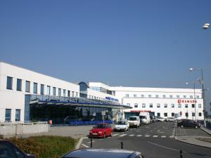 un estacionamiento con autos estacionados frente a un edificio en Ramada Airport Hotel Prague en Praga