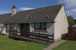 a house with a porch and a wooden fence at Kirkside Holiday Home in Alness