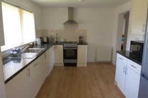 una cucina con lavandino e piano cottura forno superiore di Kirkside Holiday Home a Alness