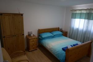 a bedroom with a bed with blue pillows and a cabinet at Kirkside Holiday Home in Alness