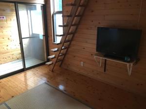 sala de estar con TV y pared de madera en Kumamoto Guesthouse Minami Aso Little Asia en Minami Aso