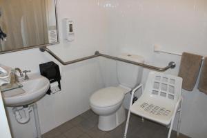 a white bathroom with a toilet and a sink at Acacia Motor Inn in Armidale