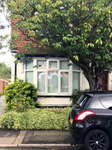 une voiture garée devant une maison avec une fenêtre dans l'établissement Watford Town centre Apartment, à Watford