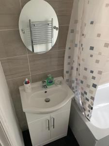 a bathroom with a sink and a mirror and a tub at Watford Town centre Apartment in Watford