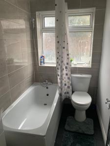 a bathroom with a toilet and a tub and a sink at Watford Town centre Apartment in Watford