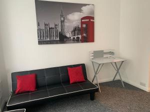 a black couch with two red pillows and a telephone booth at Watford Town centre Apartment in Watford