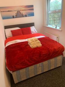 - une chambre avec un grand lit, des couvertures rouges et une fenêtre dans l'établissement Watford Town centre Apartment, à Watford