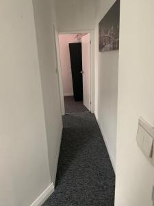 a hallway with white walls and a black door at Watford Town centre Apartment in Watford