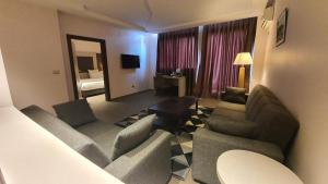 ein Wohnzimmer mit 2 Sofas und einem Tisch in einem Hotelzimmer in der Unterkunft Grand Hotel Central Conakry in Conakry