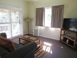 a living room with a couch and a television at Lakes Entrance Waterfront Cottages with King Beds in Lakes Entrance