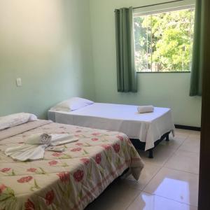 two beds in a room with a window at Suites e Flats Trancoso in Trancoso