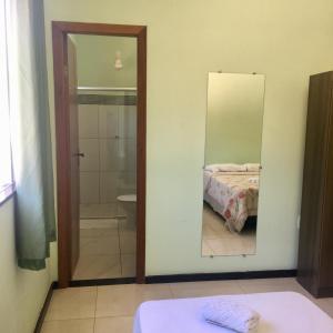 a bathroom with a mirror and a bed and a shower at Suites e Flats Trancoso in Trancoso