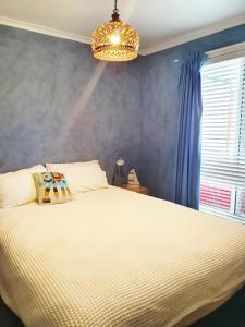 a bedroom with a white bed and a chandelier at Marazul BEST DEAL - Stone Bathtub, WIFI, Functional - Mandarins and lemons when available in Vincentia
