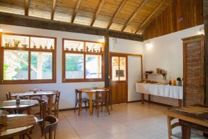 un restaurante con mesas y sillas de madera y ventanas en Morada do Gabriel, en Guarda do Embaú