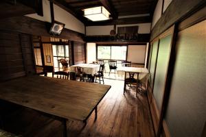 a dining room with a wooden table and chairs at ゲストハウス喜平 in Kaizuka