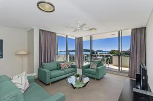 a living room with a couch and chairs and a tv at The Dalgety Apartments in Townsville