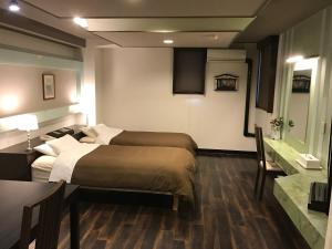 a hotel room with two beds and a table and a desk at ビジネスインホテルプラザ21大阪京橋 in Osaka